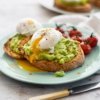Smashed avocado on toast with poached eggs and tomatoes