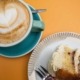 Picutre showing a slice of cake on a plate and a capuccino coffee taken from overhead