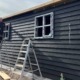 The rear view of a builder working on a new building with black cladding showing a new holiday rental coming soon
