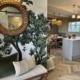 an iimage of an open planmodern licing rool with tree mural wallpaper and green and neutral soft furnishings